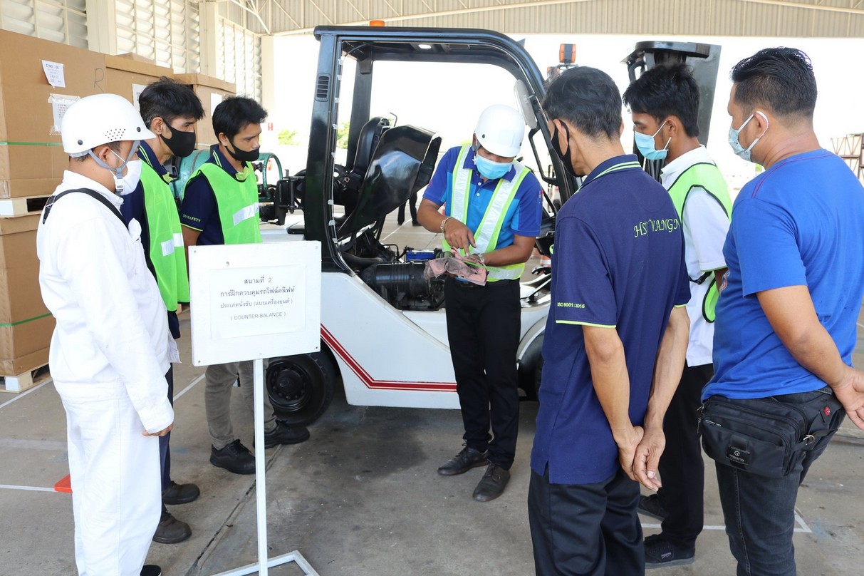 Instructor demonstrating forklift controls to a group of trainees