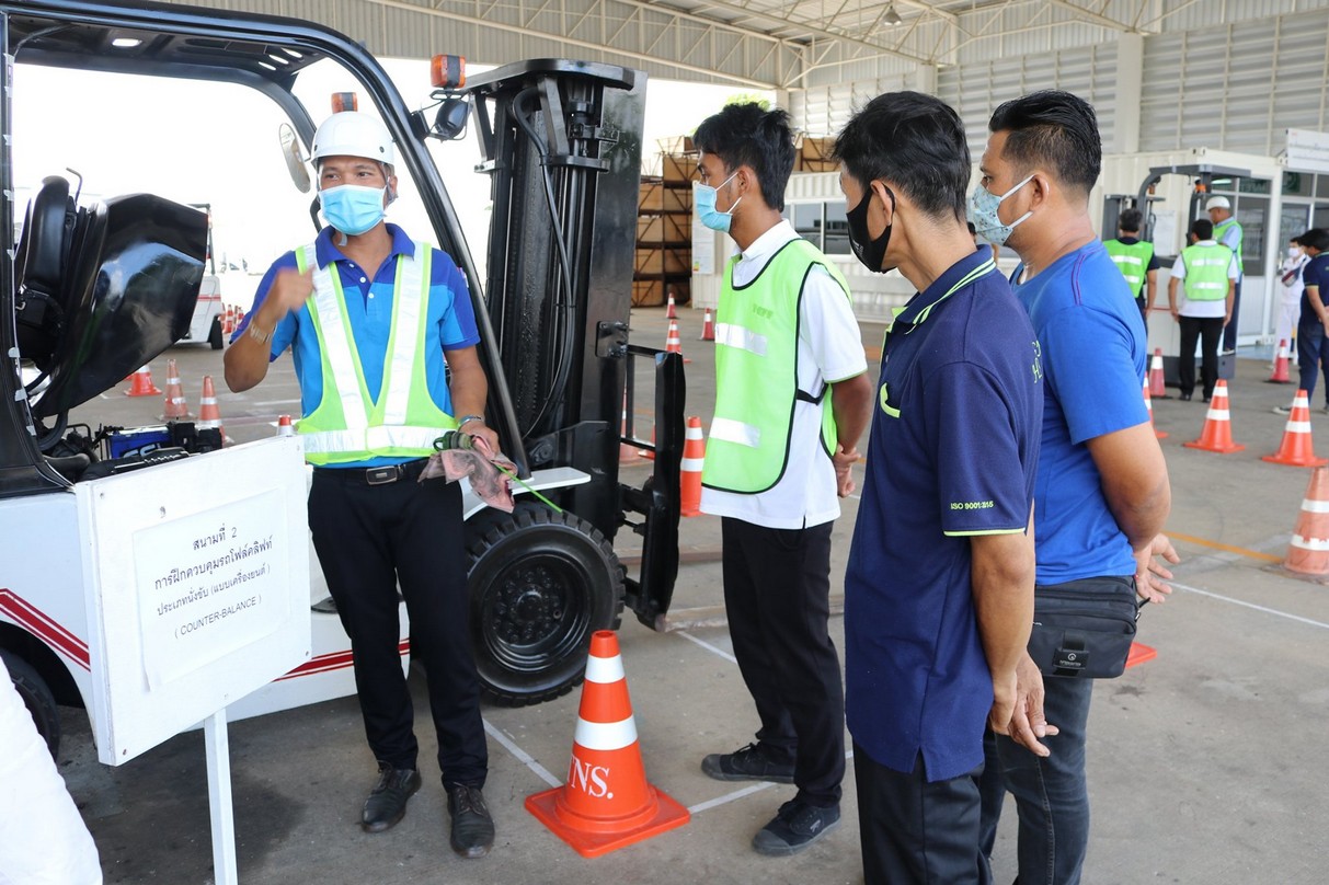 Instructor reviewing training documents with a trainee beside a forklift